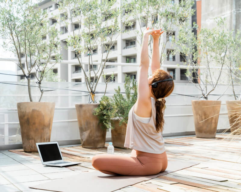 屋外で気持ちよくオンラインヨガをしている女性